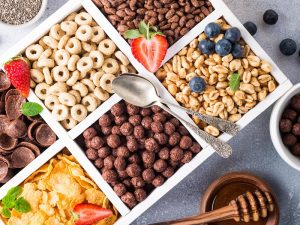 Variety of cold quick breakfast cereals with berries in white wooden box and other ingredients for breakfast, healthy eating concept, top view.